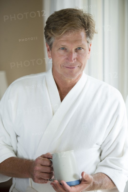 Caucasian man having coffee in bathrobe
