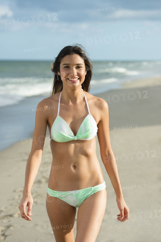 Hispanic woman walking on beach