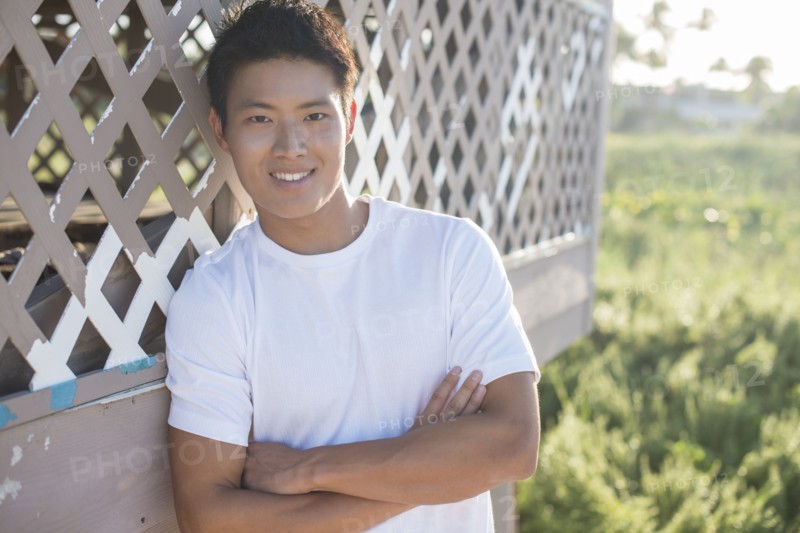 Korean man leaning against porch outdoors