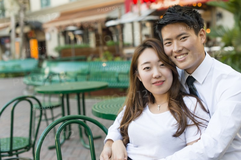 Korean couple hugging at sidewalk cafe
