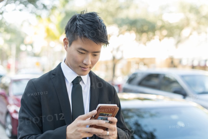 Korean businessman using cell phone outdoors