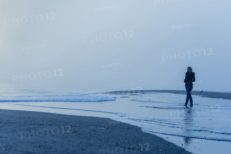 Caucasian woman walking in waves on beach
