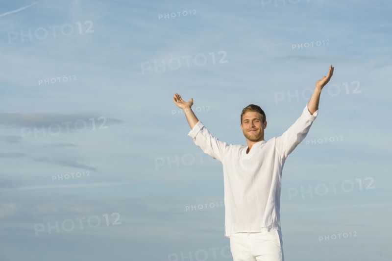 Caucasian man standing with arms raised outdoors