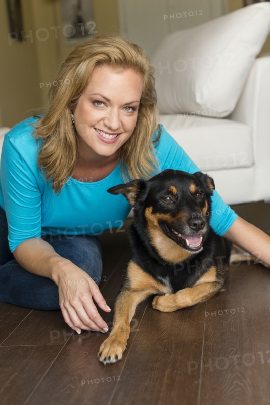 Caucasian woman playing with dog in bedroom