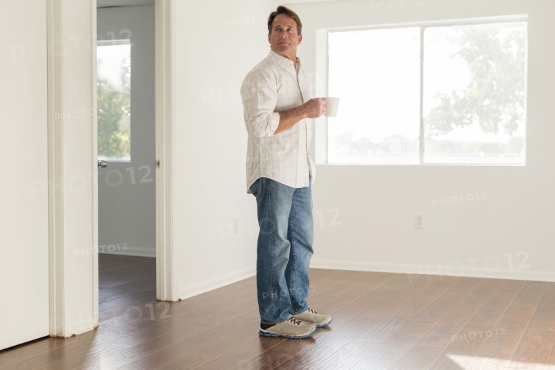 Caucasian man drinking cup of coffee in empty room
