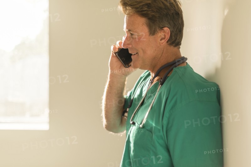 Caucasian nurse talking on cell phone near window