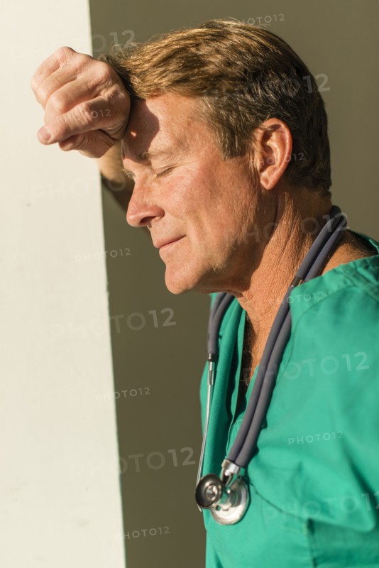 Stressed Caucasian nurse leaning on wall
