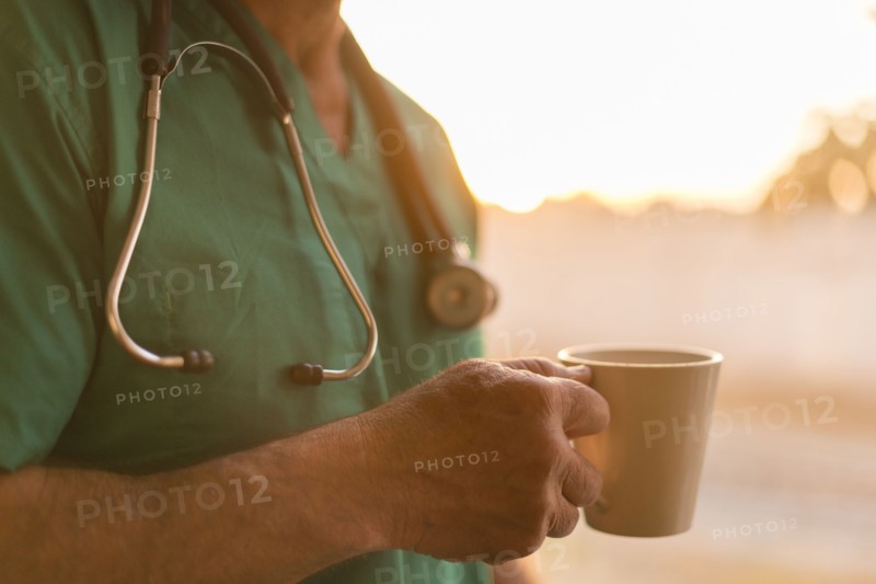 Caucasian nurse drinking cup of coffee at window