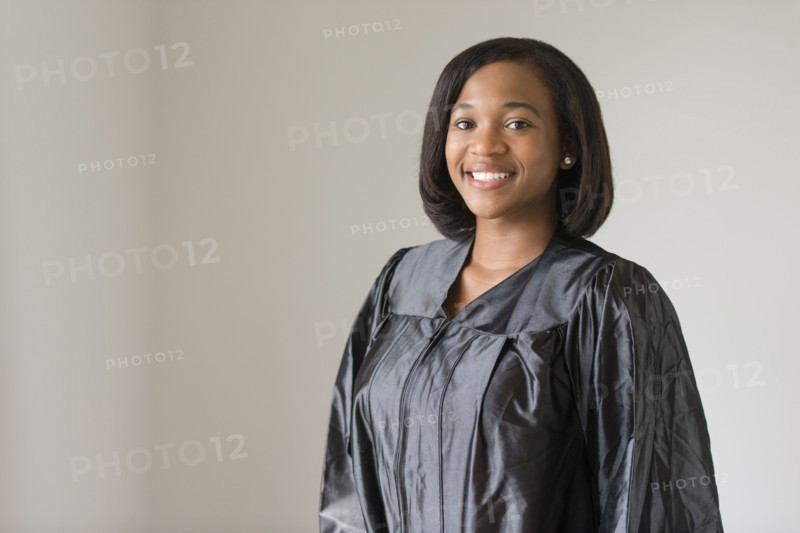 Mixed race graduate smiling in graduation robe