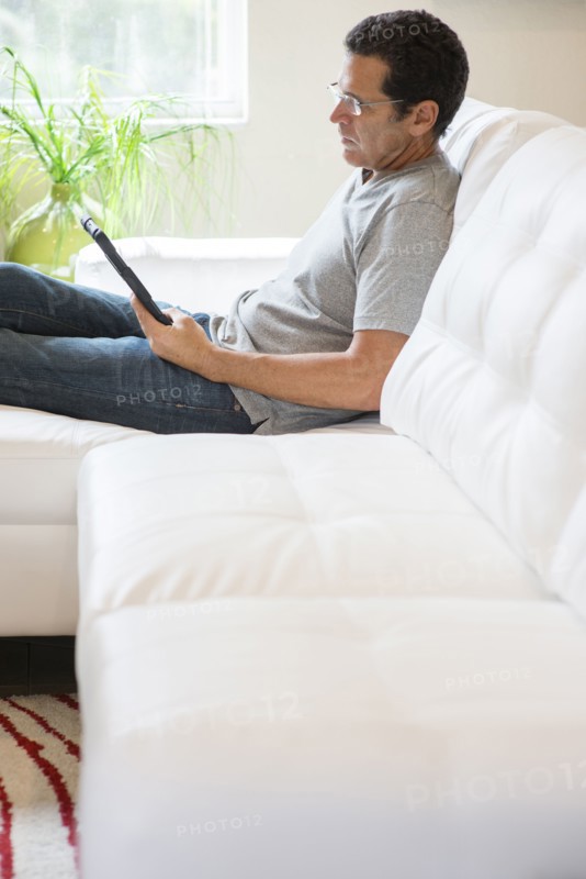 Hispanic man using digital tablet on sofa