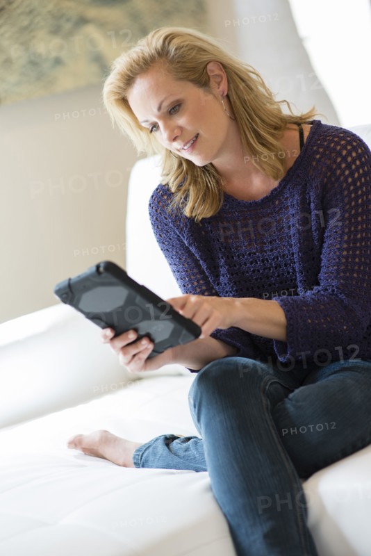 Caucasian woman using digital tablet on sofa