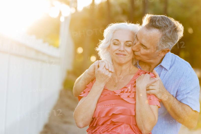 Older Caucasian couple kissing on beach