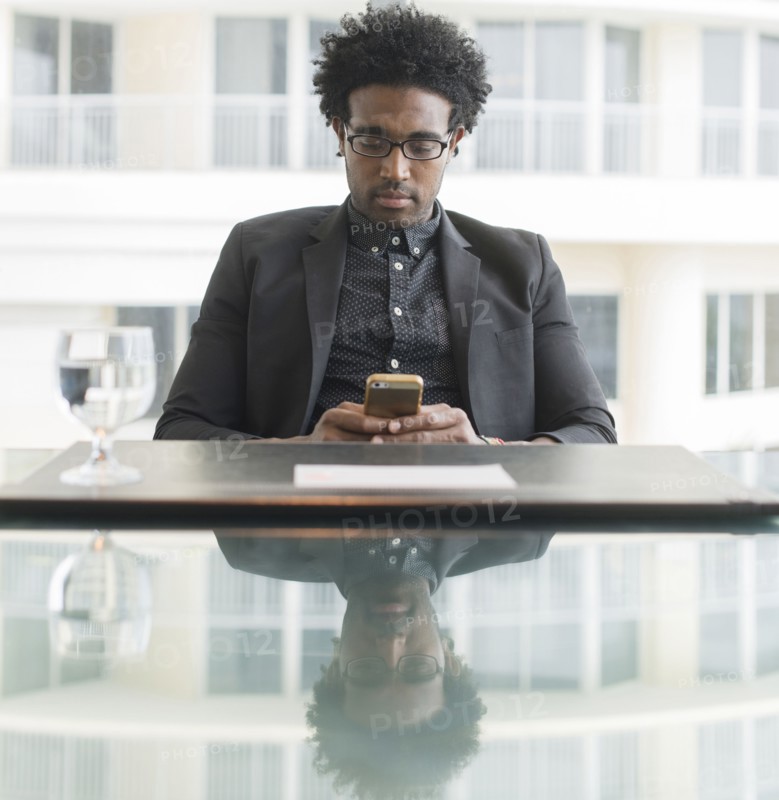Hispanic businessman using cell phone at conference table