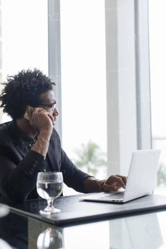 Hispanic businessman using cell phone and laptop in office