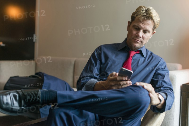 Caucasian businessman using cell phone in office lobby
