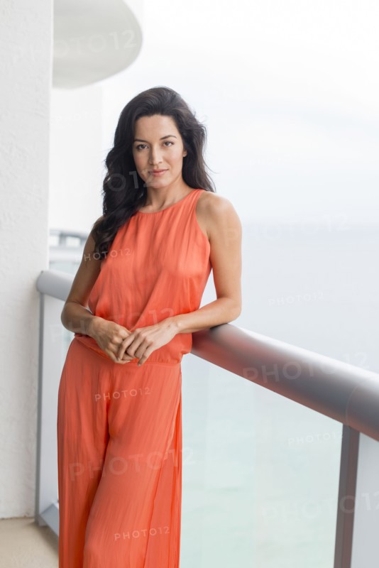 Hispanic woman leaning on balcony