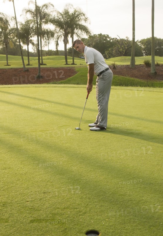 Caucasian man putting on golf course