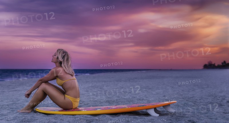Caucasian woman sitting on surfboard on beach