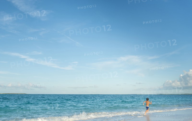 Hispanic boy running on beach