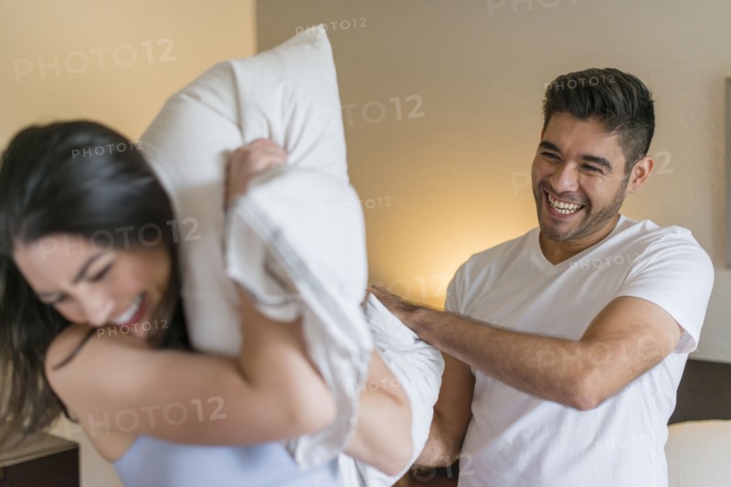 Hispanic couple having pillow fight
