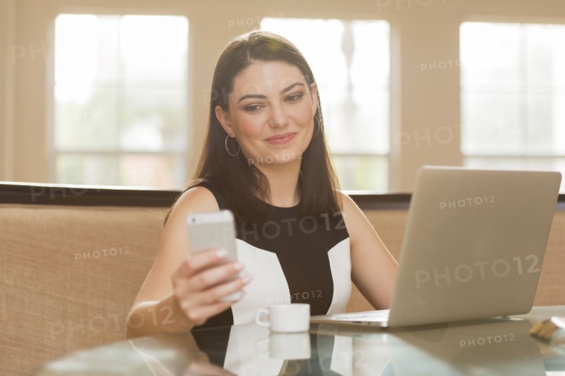 Hispanic businesswoman using cell phone in office
