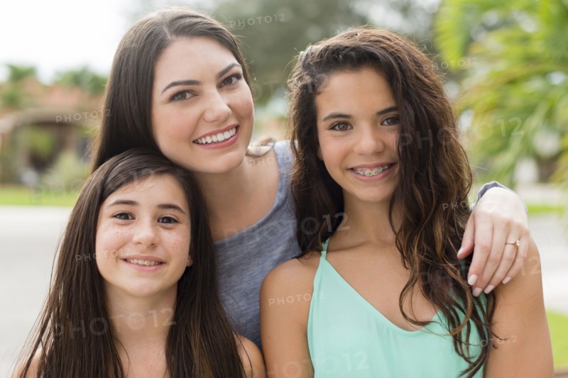 Mother and daughters smiling outdoors