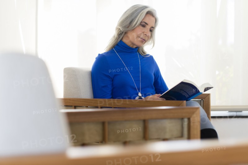 Caucasian woman reading book in armchair