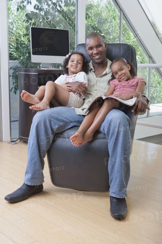 African American father holding daughters on his lap