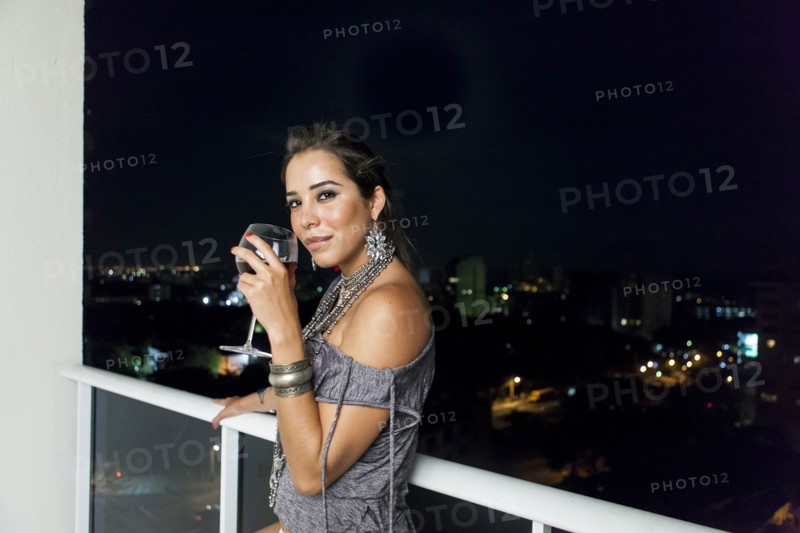 Woman drinking wine on urban balcony