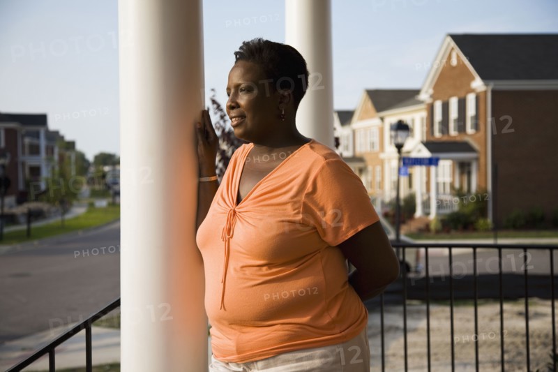 Pensive African woman standing on front stoop of house