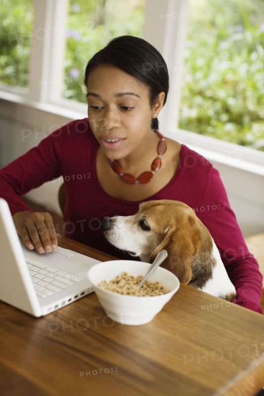 African woman with dog looking at laptop