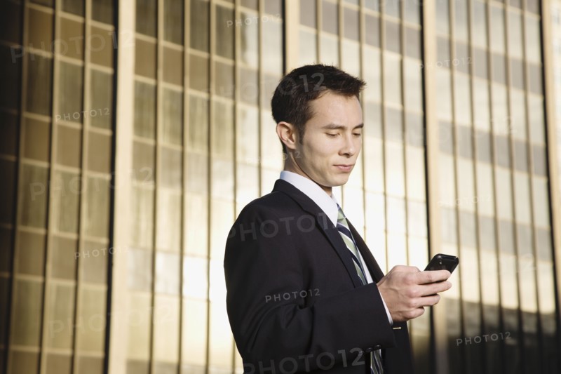 Mixed race businessman text messaging on cell phone