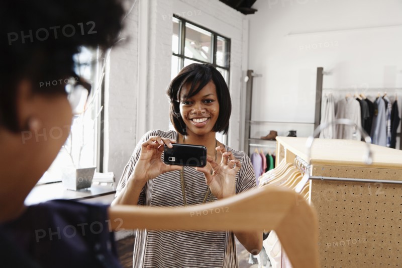 Woman taking a photograph of clothing in store