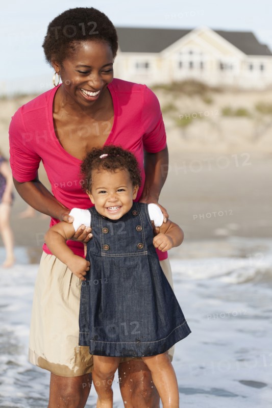 Smiling mother playing with daughter on beach