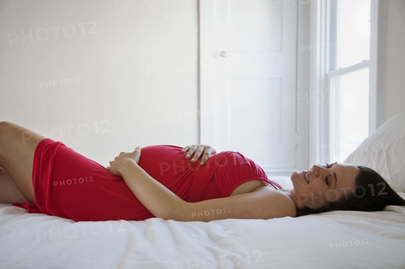 Pregnant Caucasian woman laying on bed