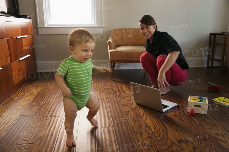 Caucasian mother watching toddler son walk