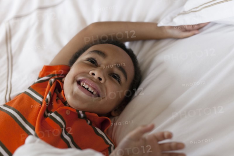 Mixed race boy laying in bed