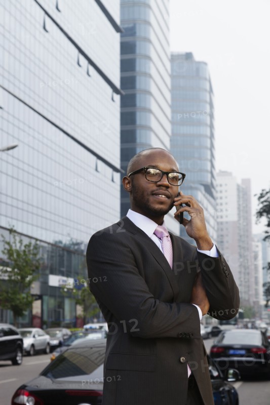 Black businessman talking on cell phone on city street