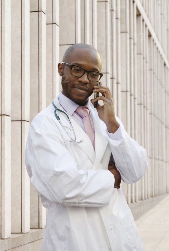 Black doctor talking on cell phone on city street