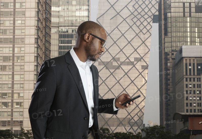 Black businessman using cell phone on city street