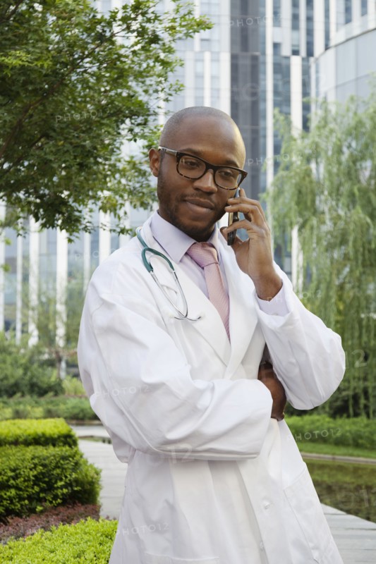 Black doctor talking on cell phone in urban park