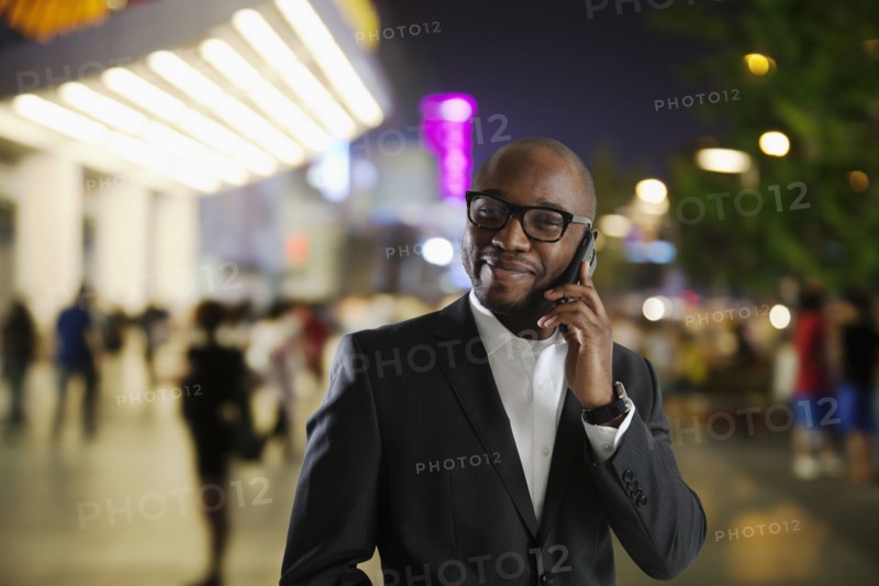 Black businessman talking on cell phone on city street