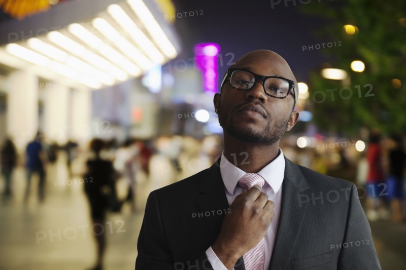 Black businessman adjusting tie on city street