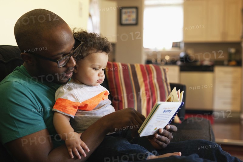 Father reading to baby on sofa