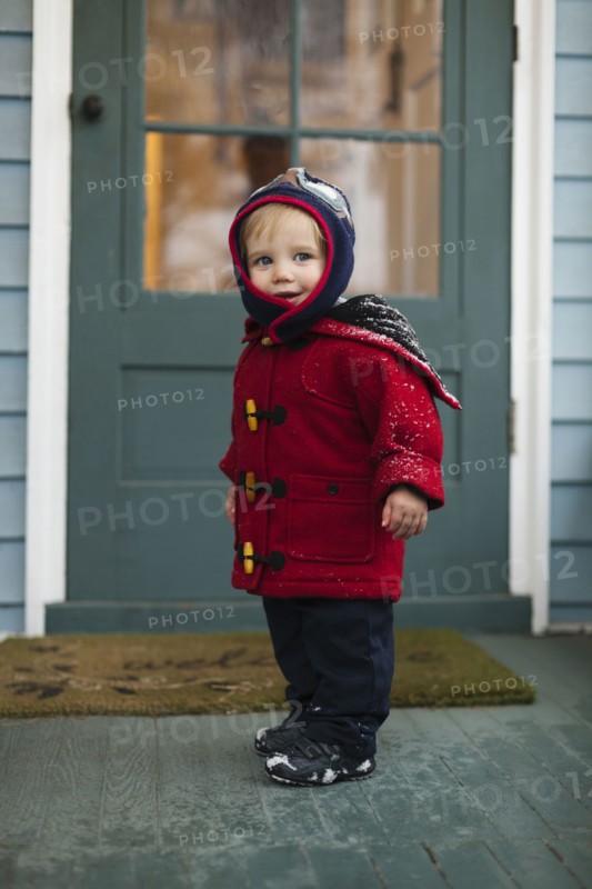 Caucasian boy wearing winter coat on porch