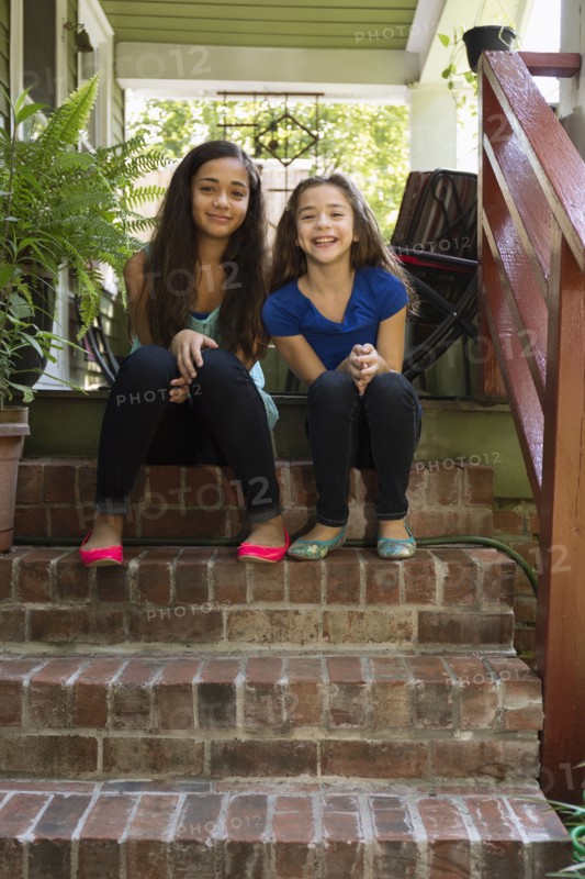 Mixed race sisters sitting on steps