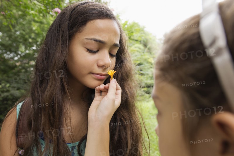 Mixed race girls smelling flowers