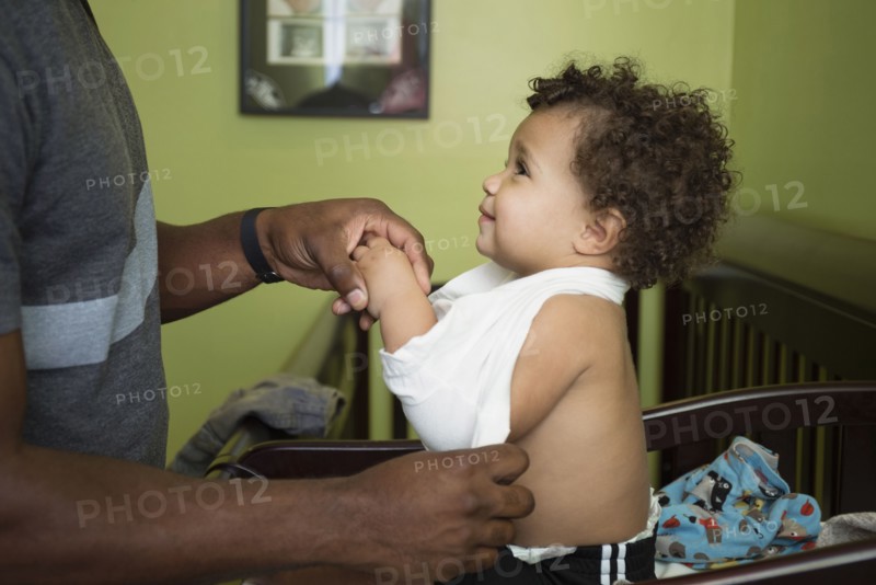 Father changing toddler son's clothes in nursery