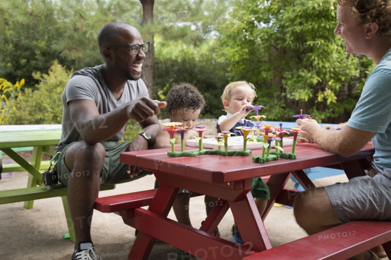 Fathers and toddler sons playing at picnic table
