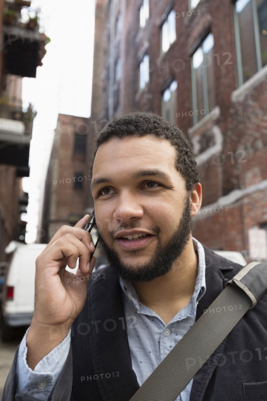 Mixed race businessman talking on cell phone in city